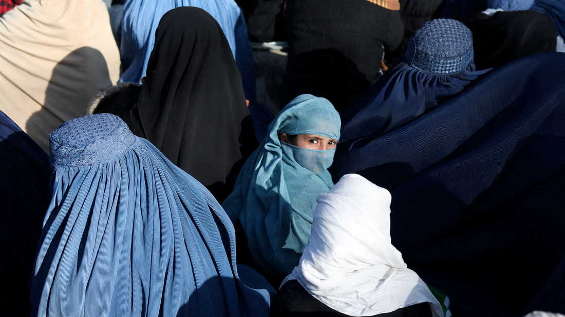 A girl sits in front of a bakery in the crowd with Afghan women waiting to receive bread in Kabul, Afghanistan, January 31, 2022. REUTERS/Ali Khara     TPX IMAGES OF THE DAY - RC2BAS96QGM7